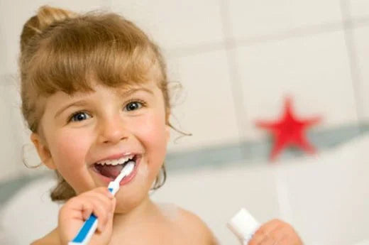 Young girl brushing teeth in bathroom using childs toothbrush